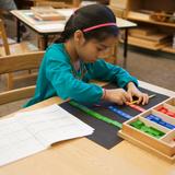 Gladwyne Montessori Photo #3 - An elementary student practices math on her own using a hands-on activity for a more in-depth understanding of the concept.