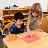 Montessori De Terra Linda Photo #5 - A five year old practices letter sounds with a younger student in the Primary (ages 3-6) class.