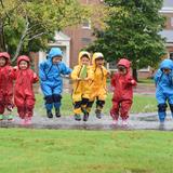 University School of Milwaukee Photo #2 - A group of Preschool students splash in a puddle outside.