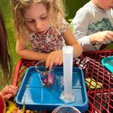 International Children's Academy Photo - Bubble, bubble, toil and trouble... we're mixing up a special potion using flower petals, shells, beads, and all sorts of materials. We're learning how to share and create all at the same time.