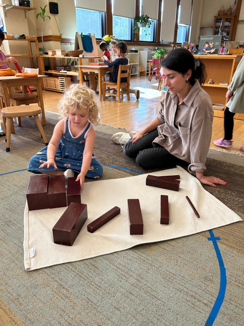 Near North Montessori Photo #1 - An engaged learner in our Primary Class for children ages 3 years to 6 years, is receiving a lesson with a Montessori material known as the brown stair. The brown stair helps children develop their awareness of size differences